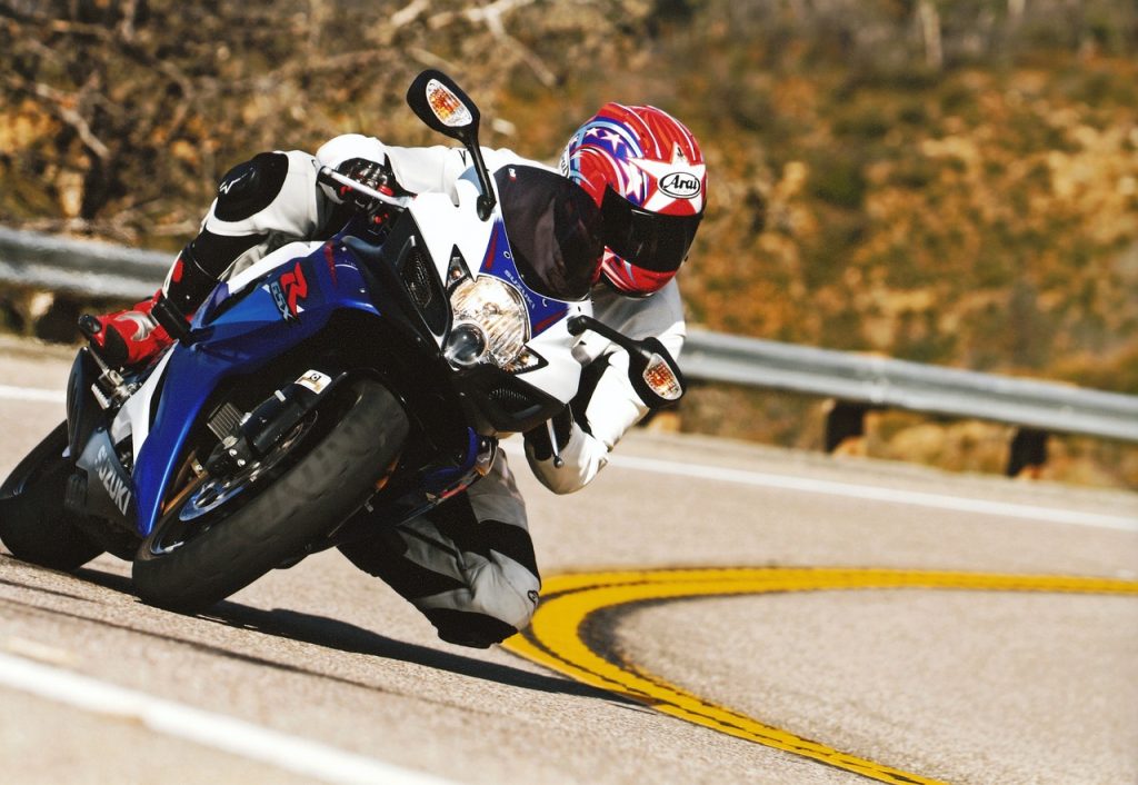 Motorradrennfahrer mit starker Schräglage in einer Kurve: Die Physik sorgt dafür, dass das Motorrad nicht umfällt.